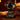 An ornate black metal gothic table lamp base shaped like pelvic bones, displayed on a wooden surface with dried red flowers and a dark red background. spine lamp gothic romantic 